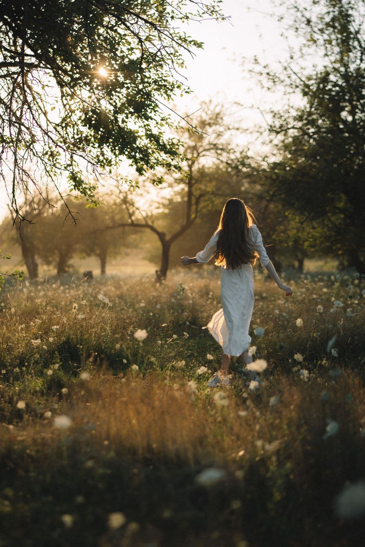 A woman walking through a sunlit meadow at golden hour