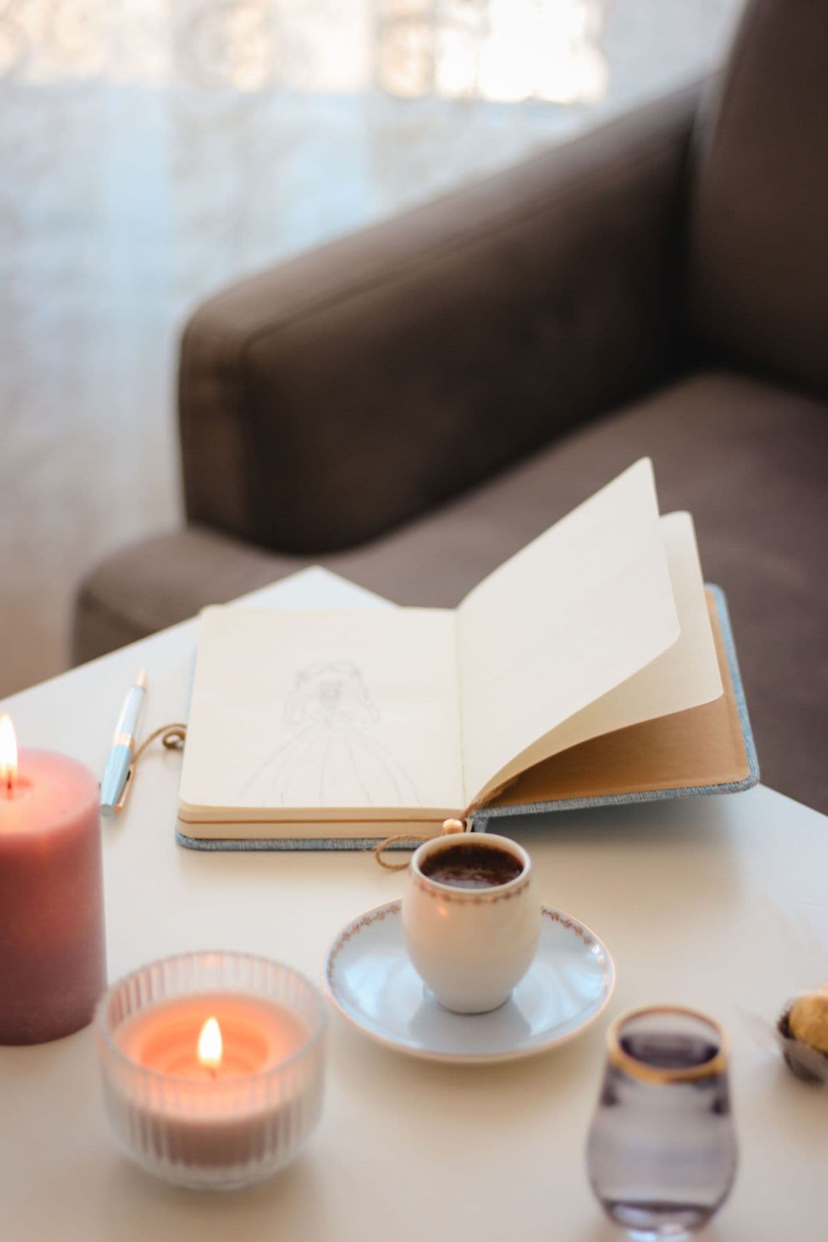 An open journal beside a glowing pink candle